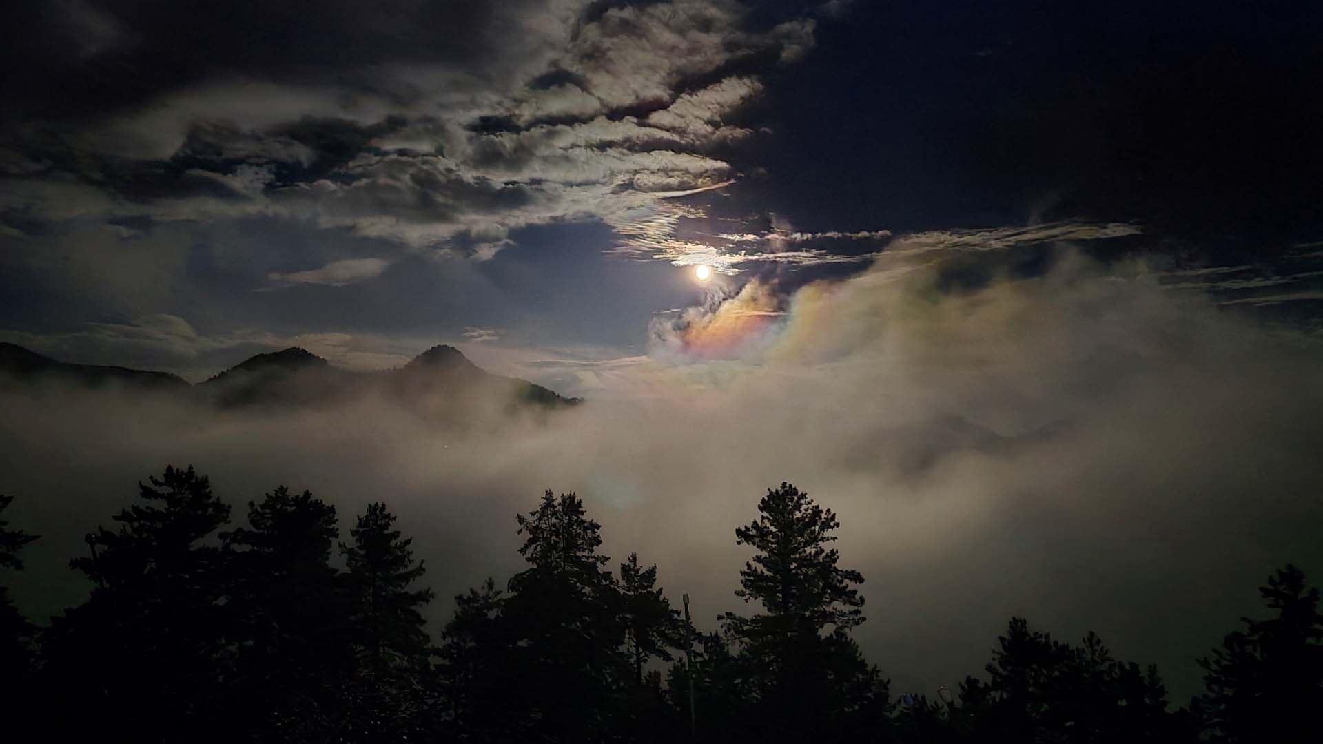 view of the mountains with sunlight streaking through the fog and clouds